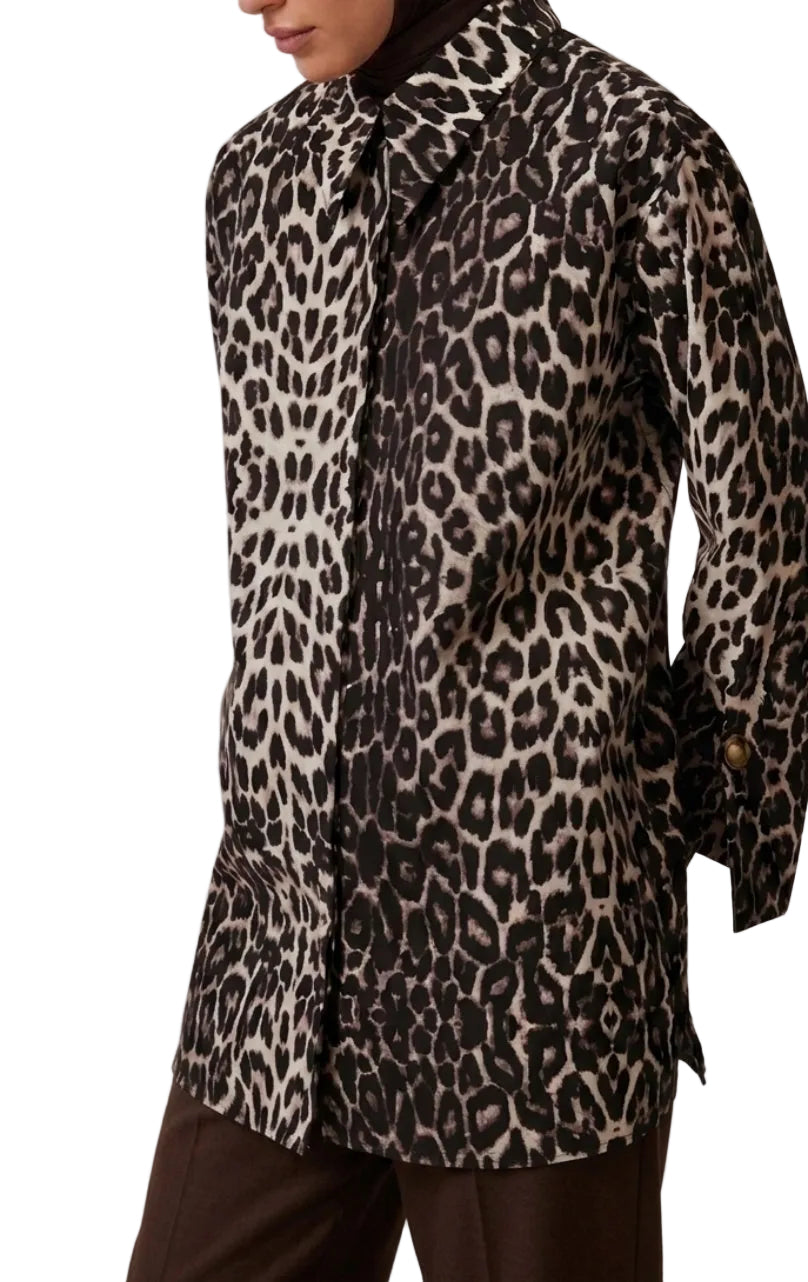 Gros plan sur le motif léopard de la chemise et sur le poignet, mettant en valeur le bouton doré et la texture du tissu 100% coton.
