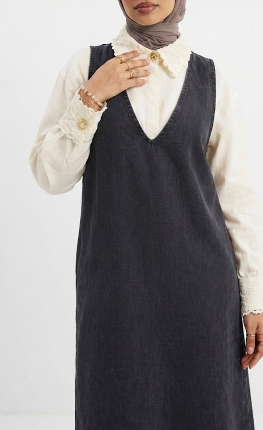 Robe longue chasuble en jean noir délavé, col V, portée avec chemise blanche - vue rapprochée